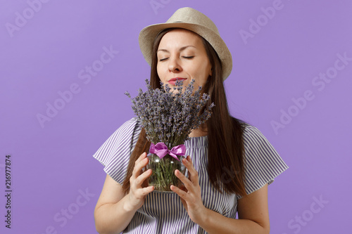 Portrait of happy young tender woman in blue dress straw hat hold and sniff bouquet of beautiful purple lavender flowers isolated on bright violet background. International Women s Day holiday concept photo