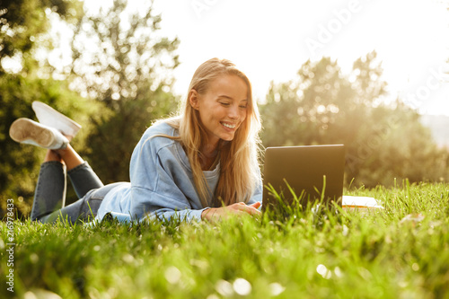 Foto Portrait of a smiling young girl laying on a grass at the park