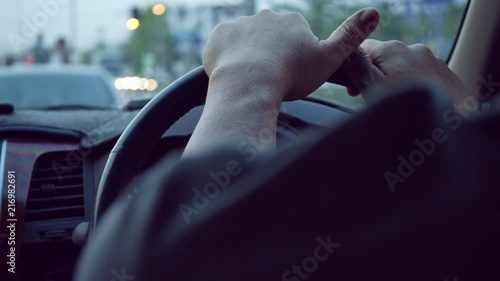 man hand holding steering wheel driving car stopped traffic jam in town