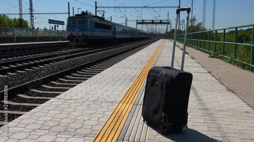 A lone suitcase on a train station platform on a sunny day