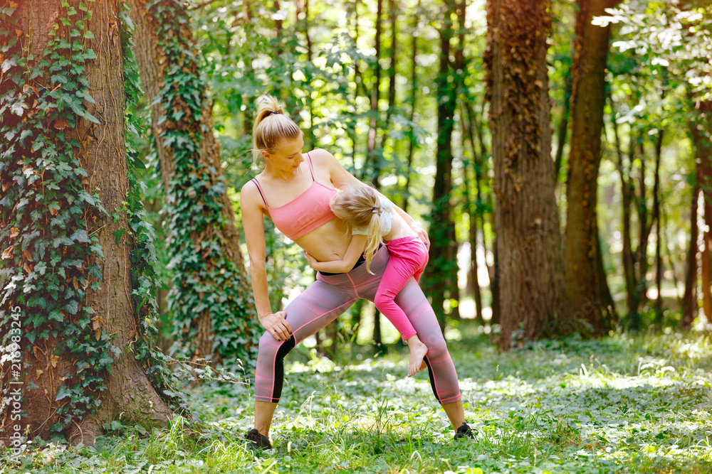 Family training. Mother and daughter exercise in park Family training. Mother and daughter exercise in park