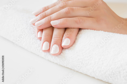 Young  perfect woman s hands with white nails on towel. Care about nails and clean  soft  smooth skin. Manicure  pedicure beauty salon.