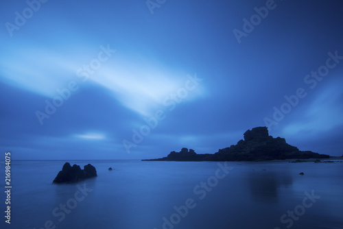 amazing ocean landscape. night time and water lige clouds and fog. rocks in the middle of the sea. long exposure with clouds in movement photo