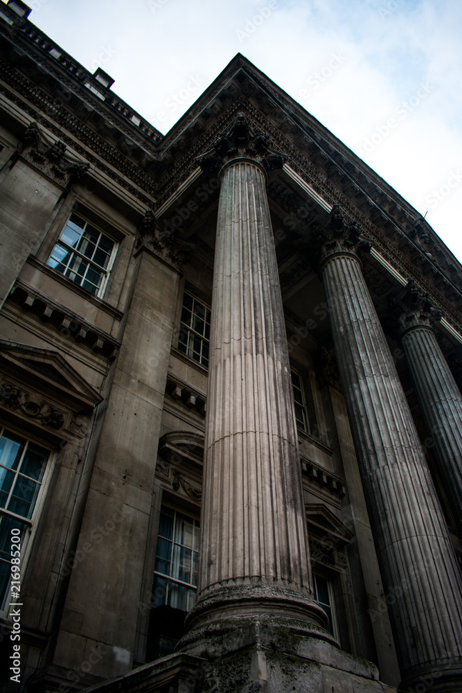An old building with columns in London, England on a cold day with a grey sky with clouds