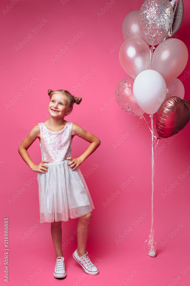 portrait of a little girl with balls, on a pink background in a photo Studio, close-up