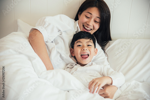 Happy loving family. Mother and her son playing on the bed in bedroom.