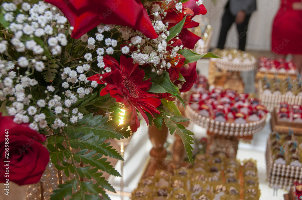 Arranjo de flores na decoração e docinhos ao fundo