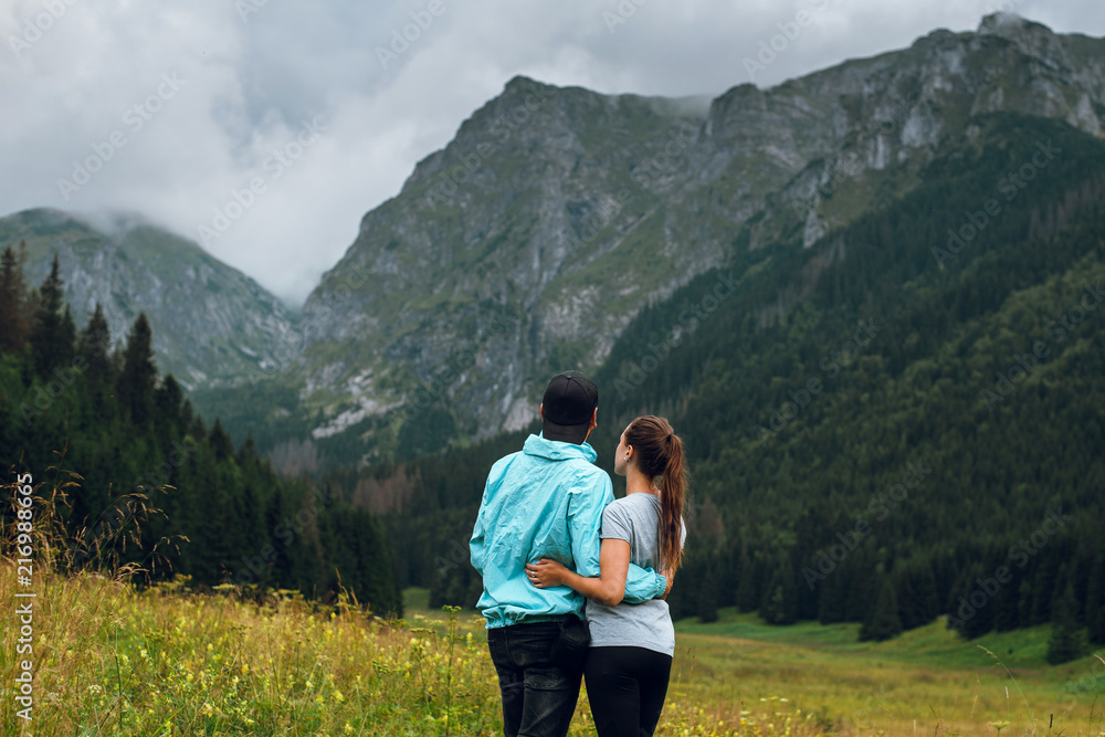 Rear view shot of young couple of man and woman enjoying beautiful view of rocky Rysy mountains, Tatras, Poland, Slovakia. Traveling concept