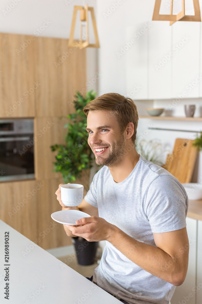 happy young man drinking coffee on breakfast at kitchen table happy young man drinking coffee on breakfast at kitchen table