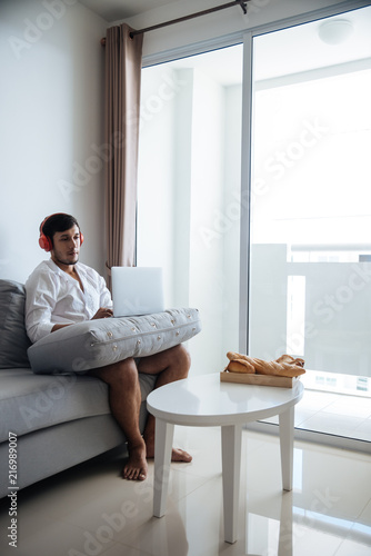 Happy man relaxing on the sofa listening to music with laptop at home