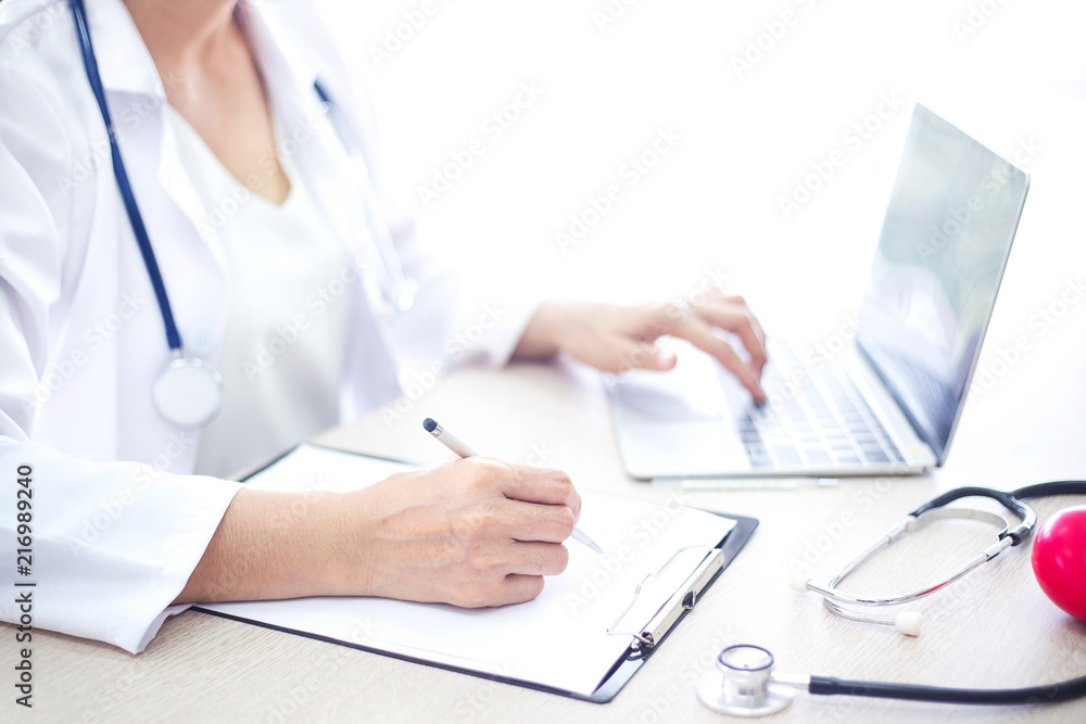 female doctor work with computer and pape note at clinic of hospital female doctor work with computer and pape note at clinic of hospital
