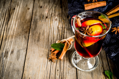 Classic winter autumn hot drink, mulled wine cocktail with spices, with plaid and Christmas tree branches, on a wooden background, copy space for text