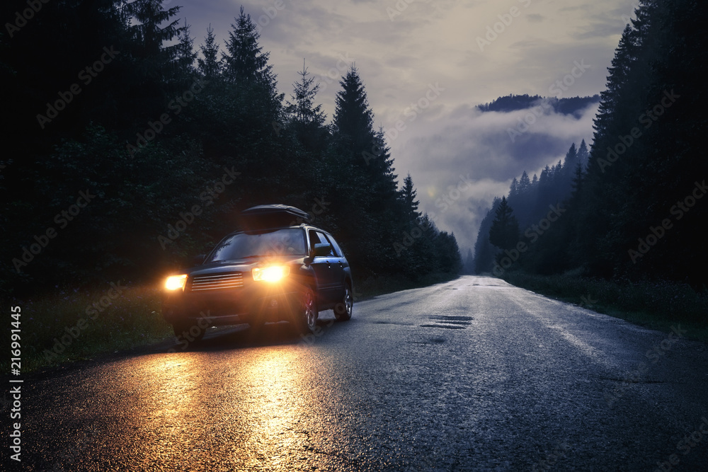Car with headlights on at night road - obrazy, fototapety, plakaty 