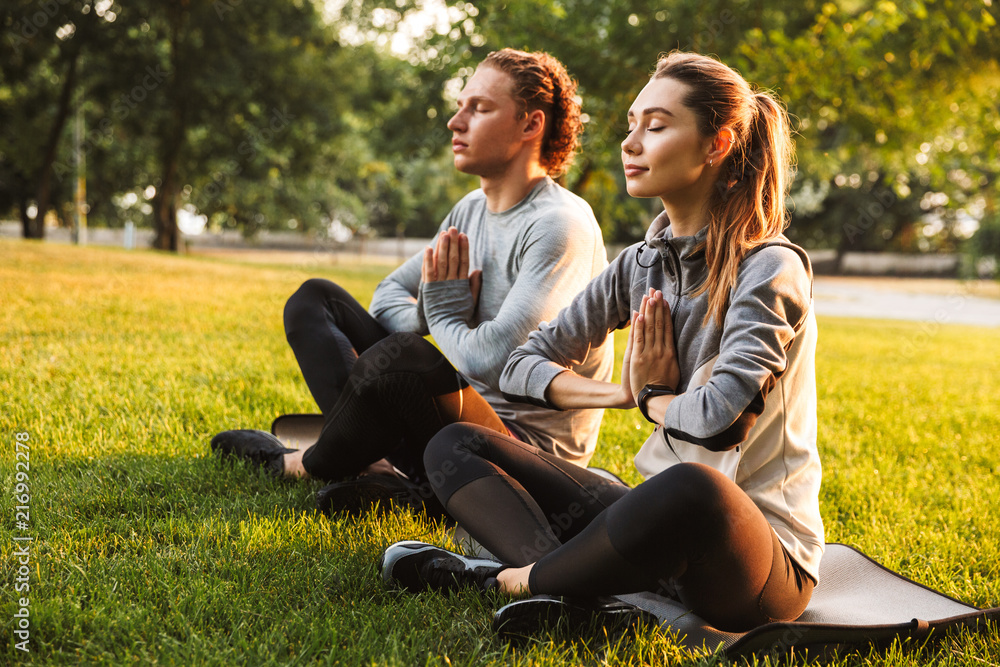 Fitness loving couple friends in park make meditate exercises. - obrazy, fototapety, plakaty 