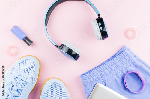 Woman sneakers, headphones, fitness tracker and running clothes on pastel background. Sport fashion concept. Flat lay