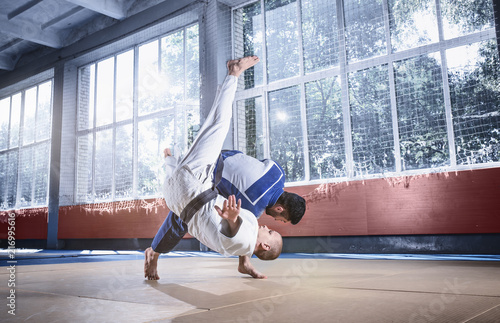 Two judo fighters showing technical skill while practicing martial arts in a fight club. The two fit men in uniform. fight, karate, training, arts, athlete, competition concept