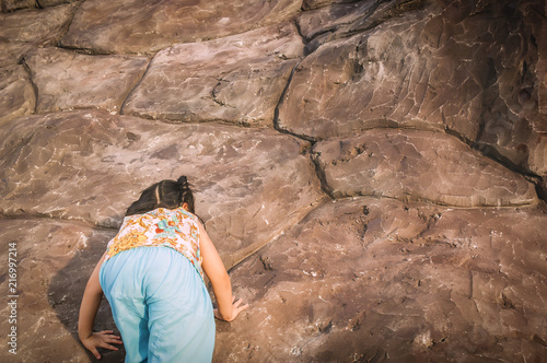 Little Girl is climbing a cliff.