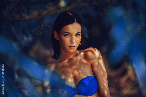 Beautiful young woman in a bikini in the shade under the tree