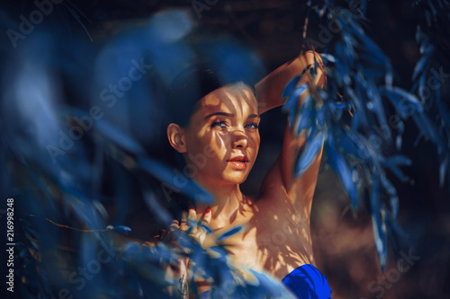 Beautiful young woman in a bikini in the shade under the tree