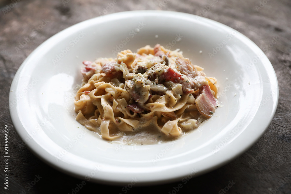 Pasta white sauce with bacon and mushroom on wood background in mystic light