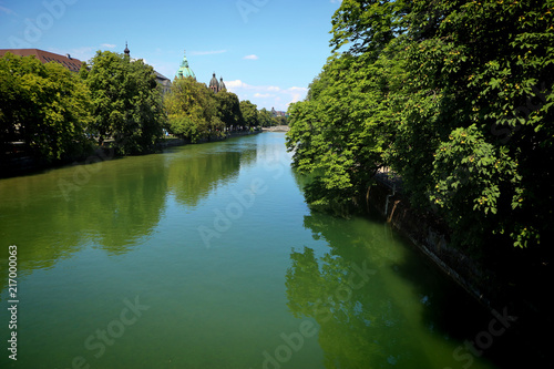 Munich, Germany - Summer view of the Isar river in Munich center city, plenty of blue green clean waters and luxurious vegetation on the river banks.