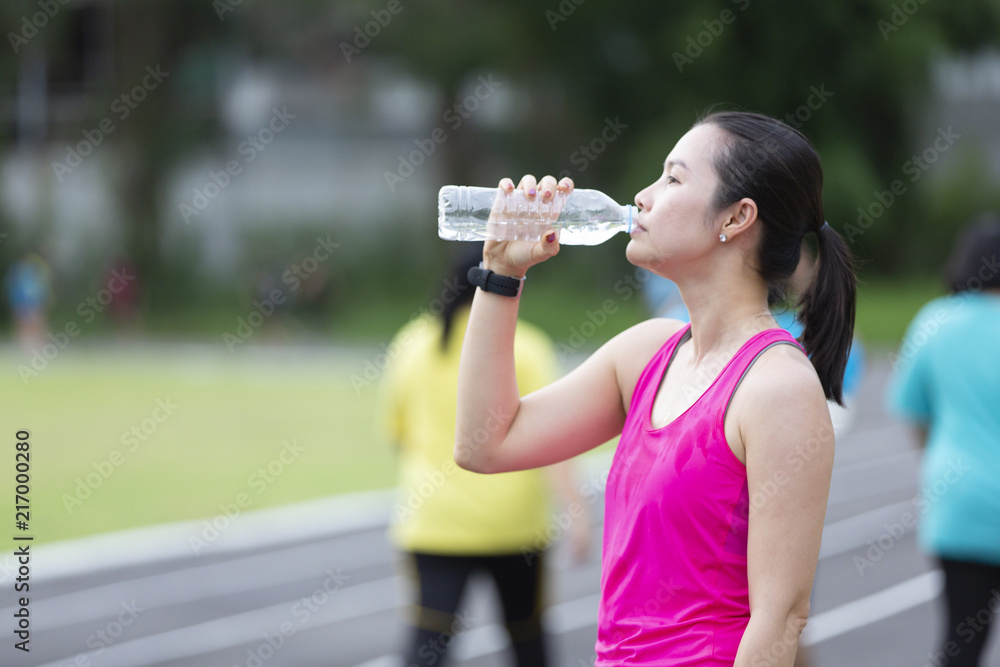 Asia woman drinking water after jogging in the park. Asia woman drinking water after jogging in the park.