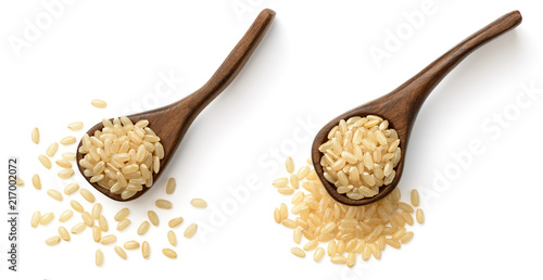 raw brown rice in the wooden spoon, isolated on the white background, top view