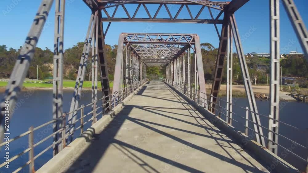 Drone flying through an old rainway bridge next to a river and beach. Drone flying through an old rainway bridge next to a river and beach.