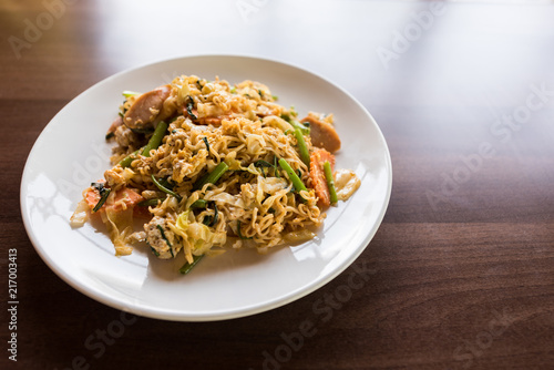 noodle fried with vegetables on wooden table near windows