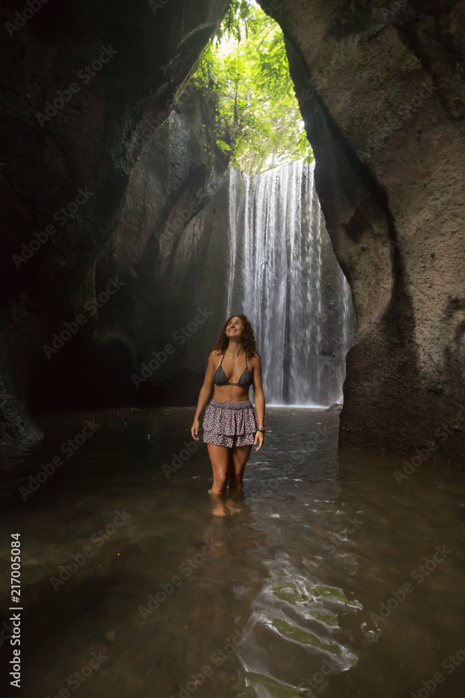Young woman at the waterfall in jungles. Ecotourism concept