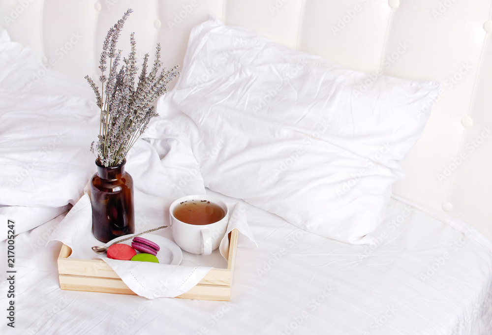 Morning breakfast in bed wooden tray with a cup of tea, sweet colorful french macaroons, love letter, bouquet of lavender. Top view Morning at Hotel or at home. Background Concept Cozy morning Morning breakfast in bed wooden tray with a cup of tea, sweet colorful french macaroons, love letter, bouquet of lavender. Top view Morning at Hotel or at home. Background Concept Cozy morning