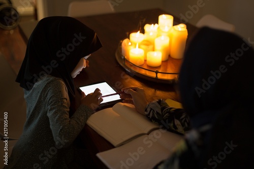 Muslim woman helping her daughter with homework photo