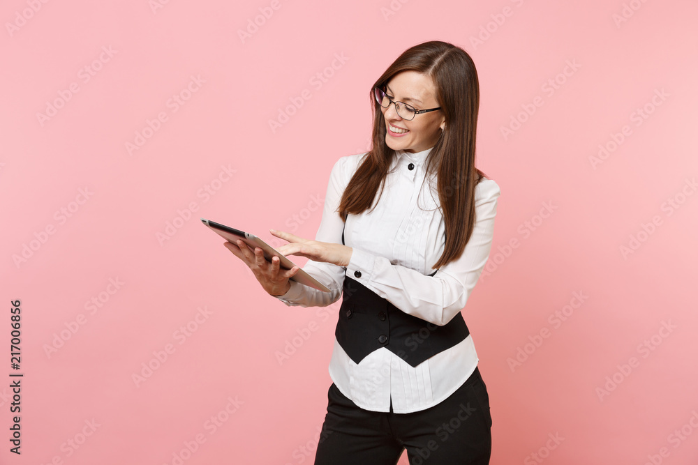 Young pleasant beautiful brunette business woman holding and using tablet pc computer isolated on pastel pink background. Lady boss. Achievement career wealth concept. Copy space for advertisement. Young pleasant beautiful brunette business woman holding and using tablet pc computer isolated on pastel pink background. Lady boss. Achievement career wealth concept. Copy space for advertisement.
