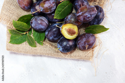 Plums on rustic background. Half of blue plum fruit. Many beautiful plums with leaves