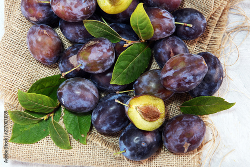 Plums on rustic background. Half of blue plum fruit. Many beautiful plums with leaves