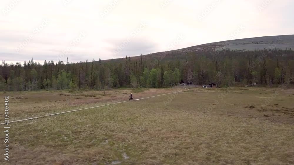 Young male fatbiking. Lapland is not only a winter destination but offers beautiful views for summer visitors as well. Located in Finland. Young male fatbiking. Lapland is not only a winter destination but offers beautiful views for summer visitors as well. Located in Finland.