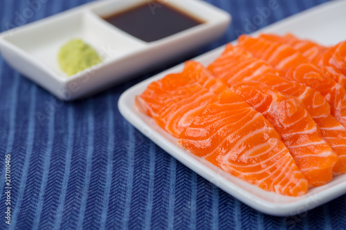 Salmon raw sashimi on whiteJapanese traditional dish on blue tablecloth.