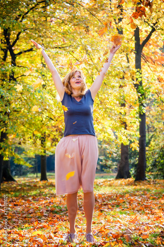 Funny young woman throw autumn leaves in the air. Vivid autumn