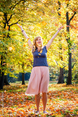 young woman throw autumn leaves in the air. vivid fall season
