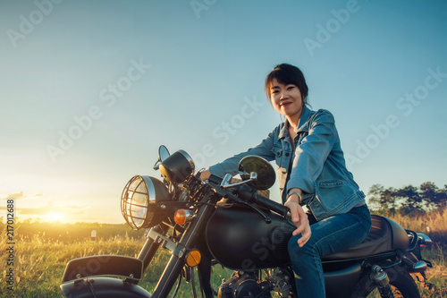 Young woman drive with motorcycle on street  enjoying freedom and active lifestyle  having fun on a bikers tour on sunset background.