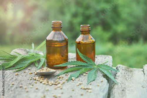 hemp leaves on wooden background, seeds, cannabis oil extracts in jars.