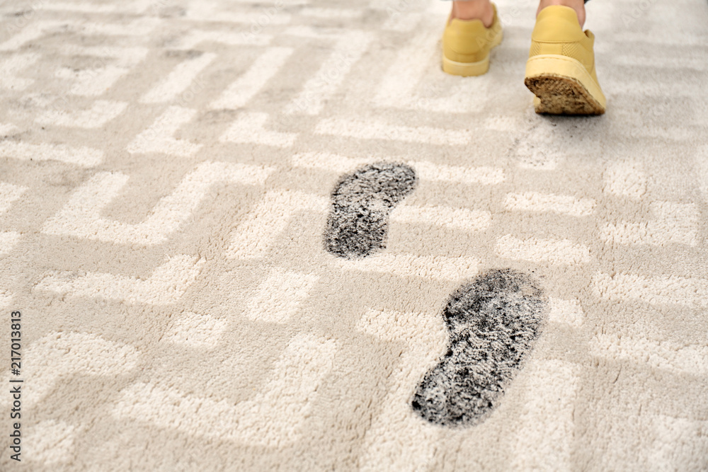 Person in dirty shoes leaving muddy footprints on carpet - obrazy, fototapety, plakaty 