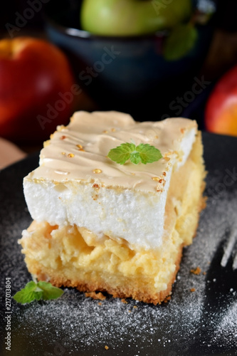 Piece of meringue pie with fruits and cottage cheese on a dark plate