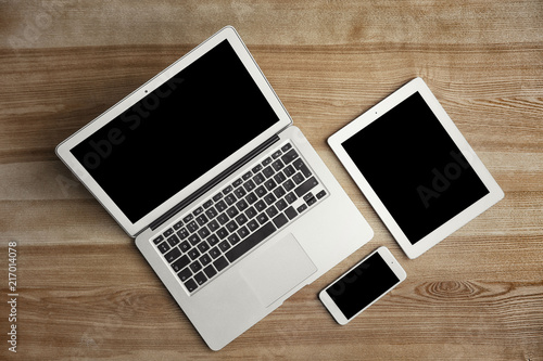 Devices with blank screens on wooden background, top view. Mock up for design