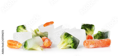 Frozen vegetables and ice cubes on white background