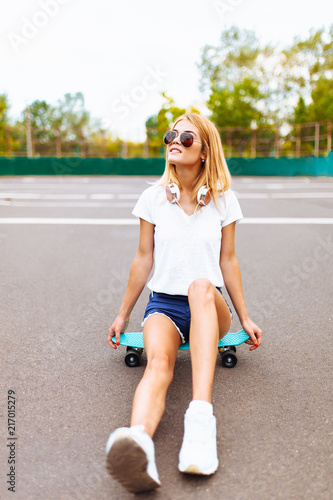 Portrait of beautiful girl with skateboard, sunglasses and headphones, isolated, summer mood