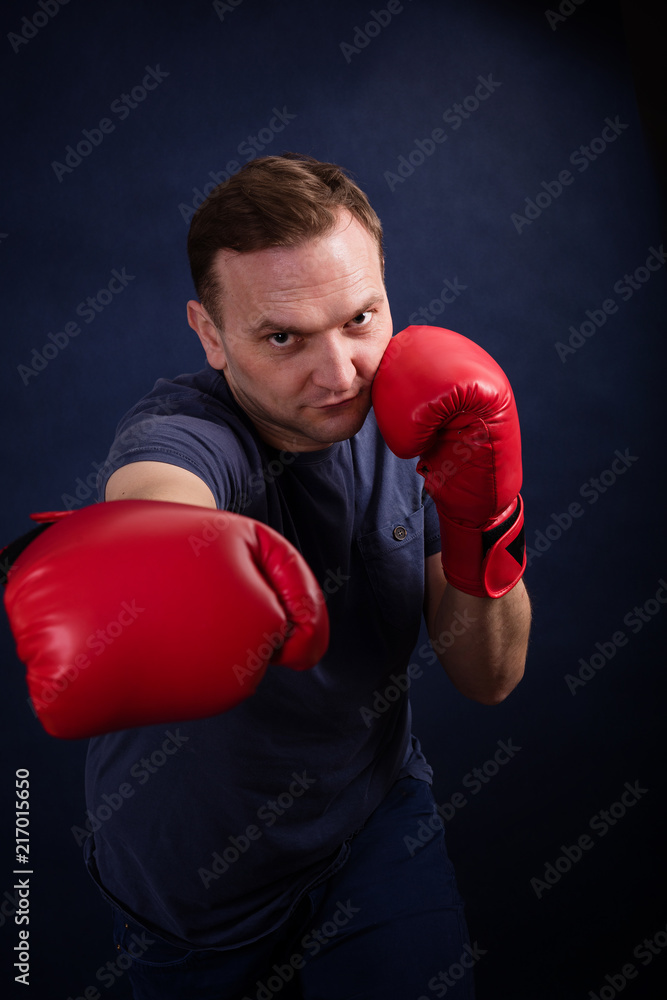 Middle aged boxer amateur trains on a dark background