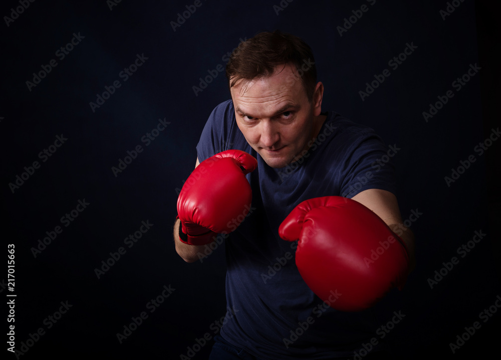 Middle aged boxer amateur trains, photo on a dark background Middle aged boxer amateur trains, photo on a dark background