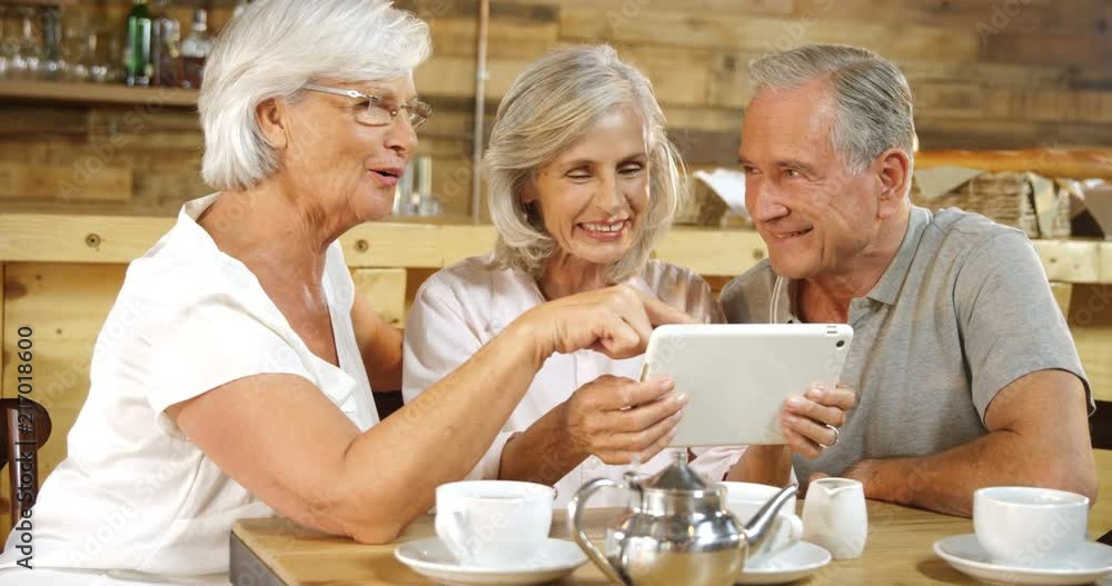 Senior friends discussing over the digital tablet in cafe 4k Senior friends discussing over the digital tablet in cafe 4k