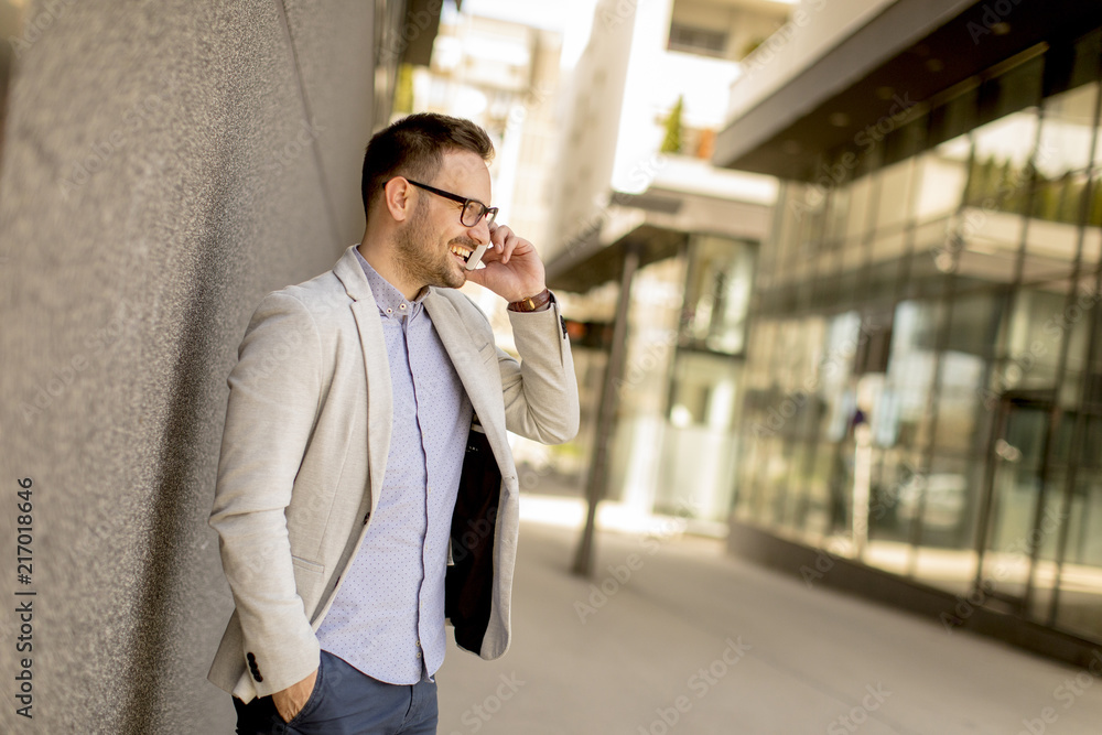 Young businessman with mobile phone by the grey wall Young businessman with mobile phone by the grey wall